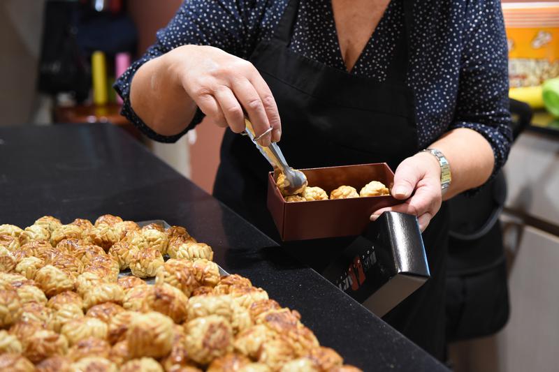 A shop assistant in a patisserie puts some pine nut panellets in boxes in October 2022