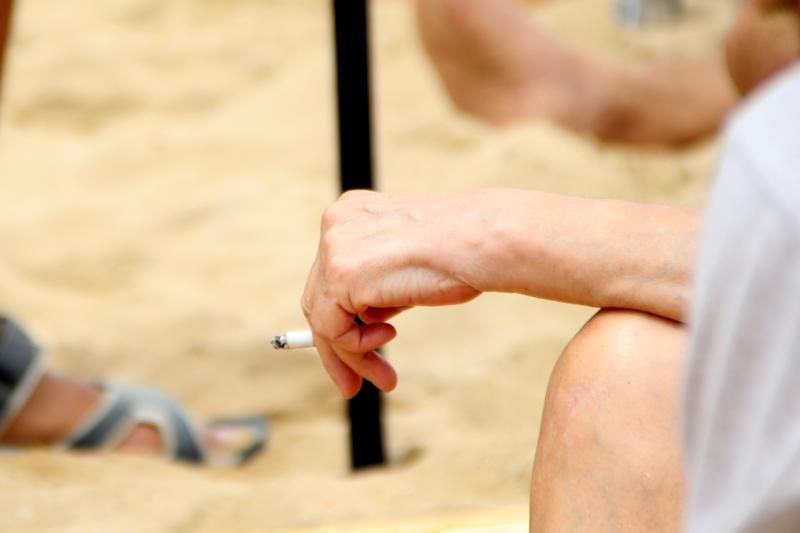 A woman holds a cigarette on Nova Icària beach in Barcelona 