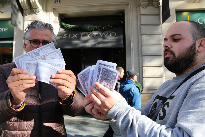 Two taxi drivers hold up fake cash bills as part of a protest denouncing illegal practices of charging tourists abusively high rates