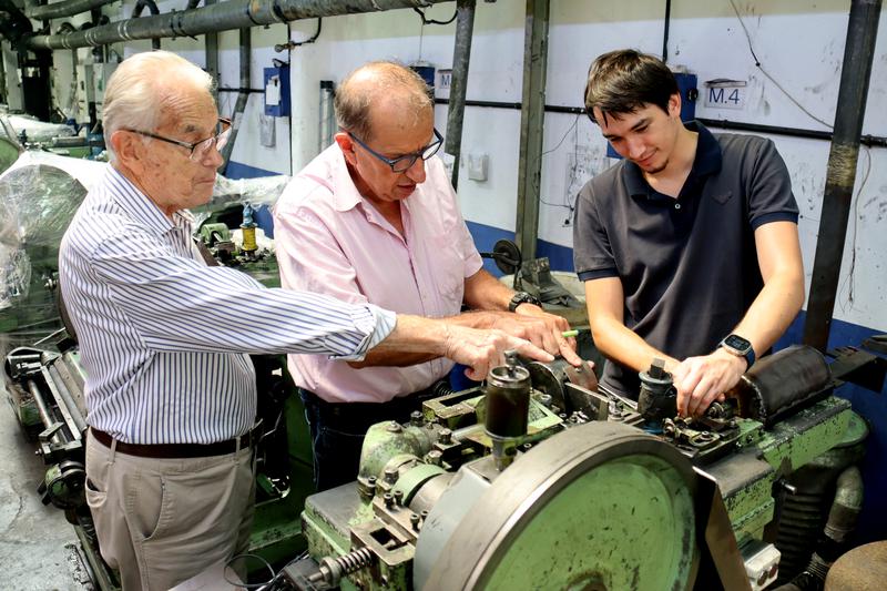 Three generations of the Folch family looking at one of the machines at their factory in Montbrió del Camp