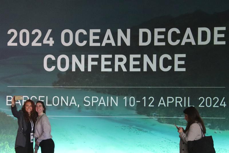 Two women taking a selfie in front of Barcelona's UNESCO 2024 Ocean Decade Conference starting on April 10, 2024