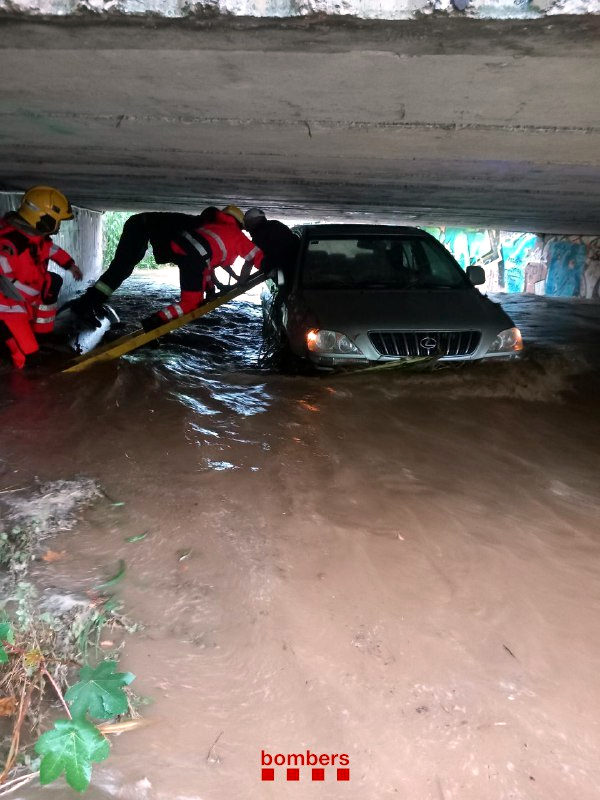 Firefighters work to rescue the man trapped in his car that was swept away by the heavy storm