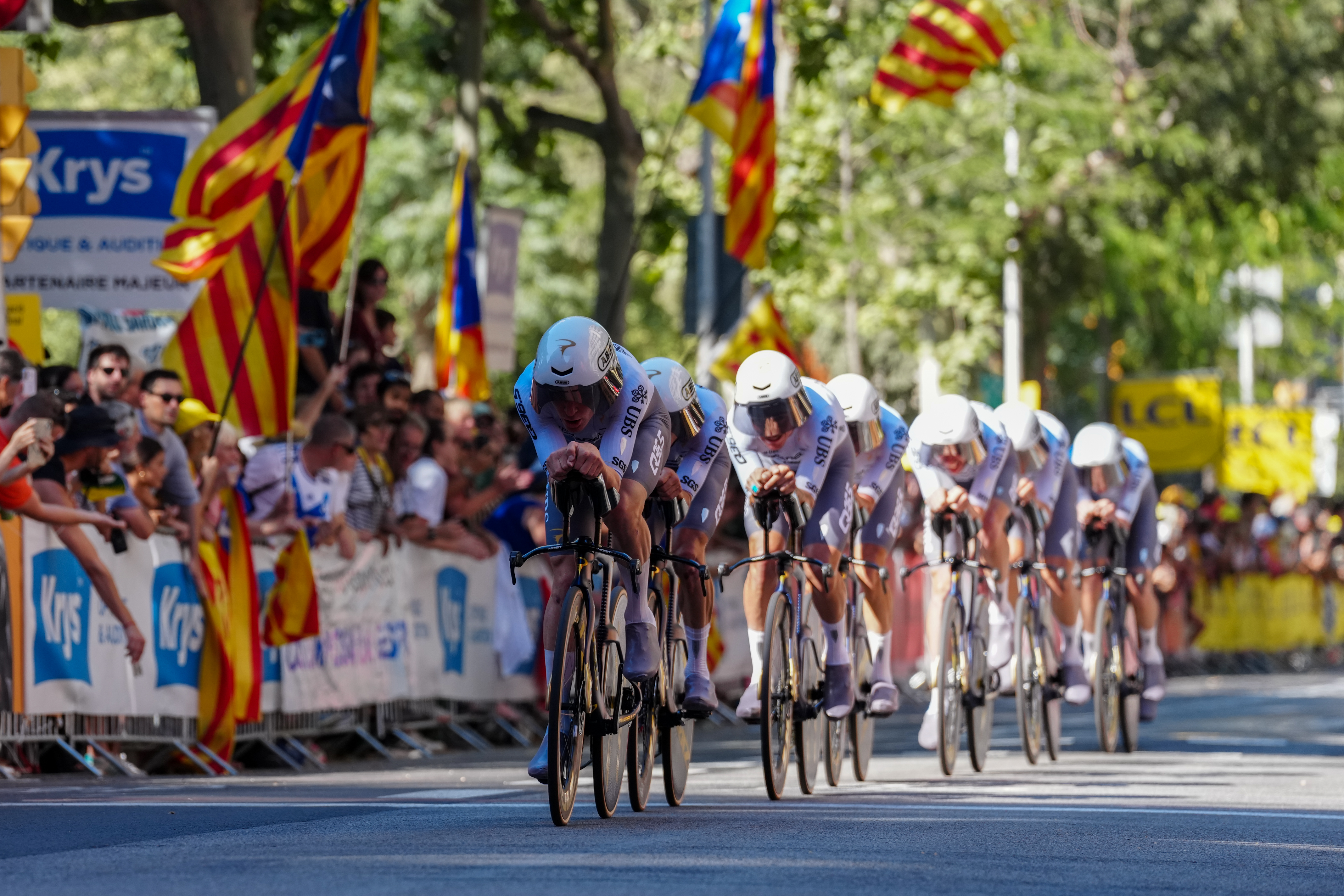Cyclists pass by the fans and flags in the first stage of the Tour