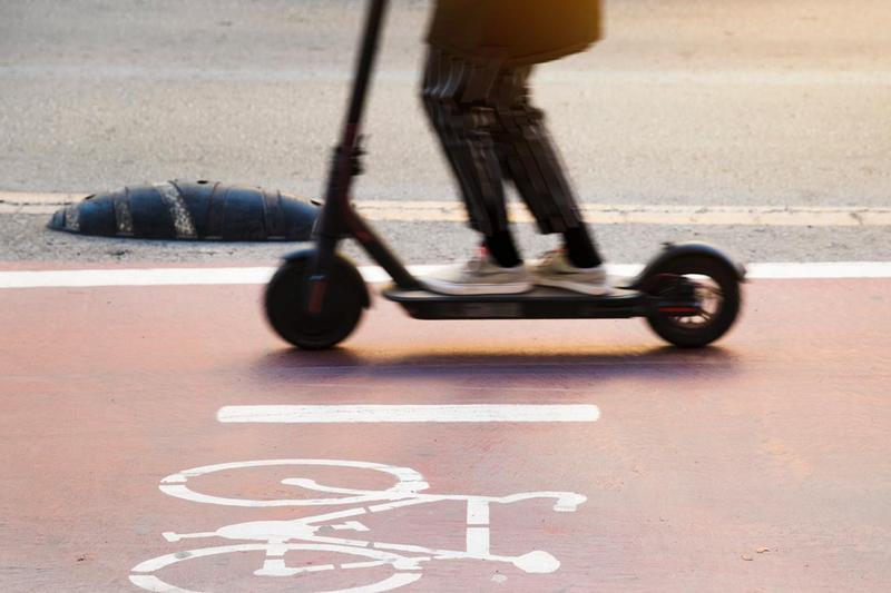 A person rides an electric scooter in a bike lane