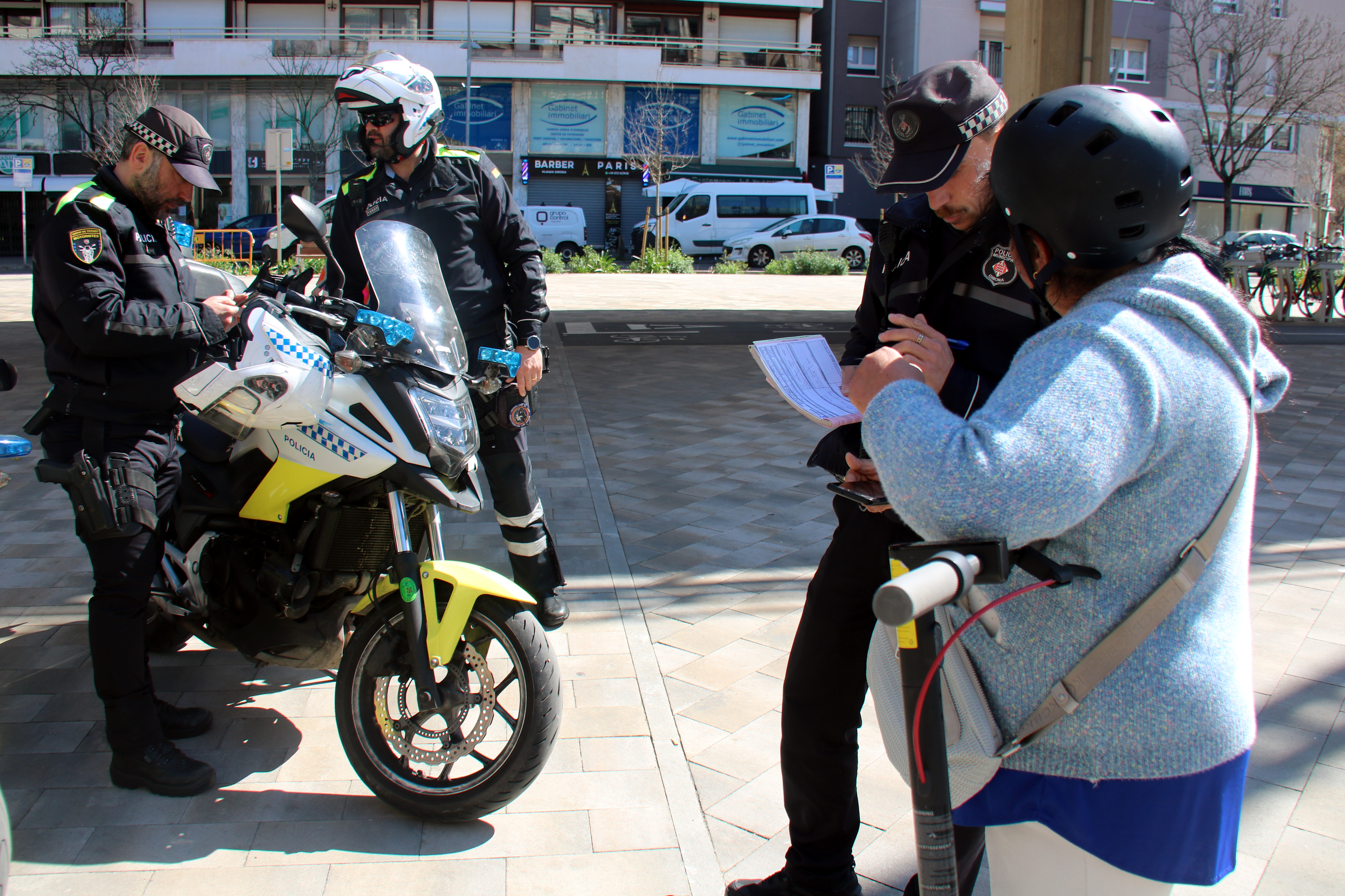 Girona Municipal Police checking that an e-scooter is insured during a traffic stop on Carrer Santa Eugènia.