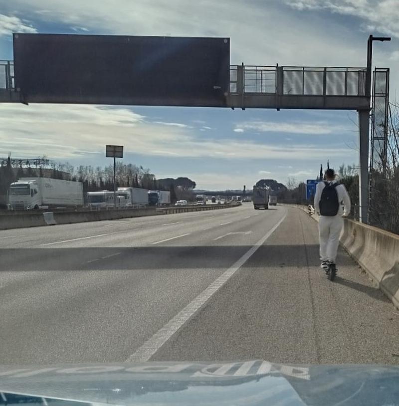 The man riding an electric scooter on the AP-7 highway in front of the police car