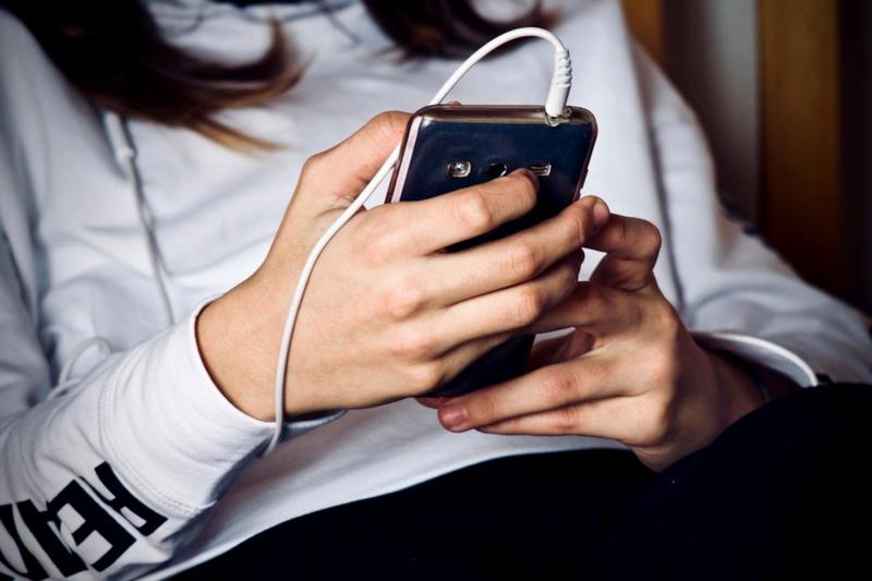 A teenager uses a cell phone. 