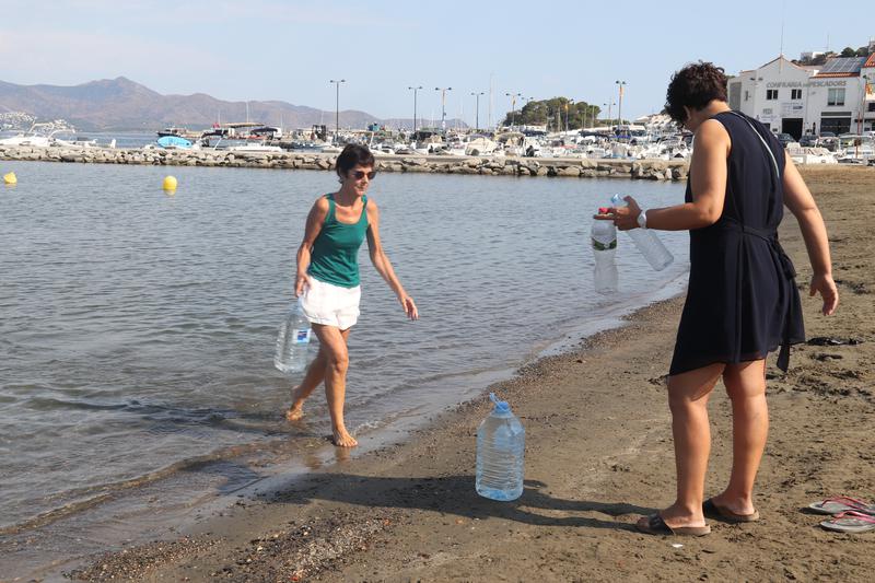 People filling water bottles in the sea in Port de la Selva.