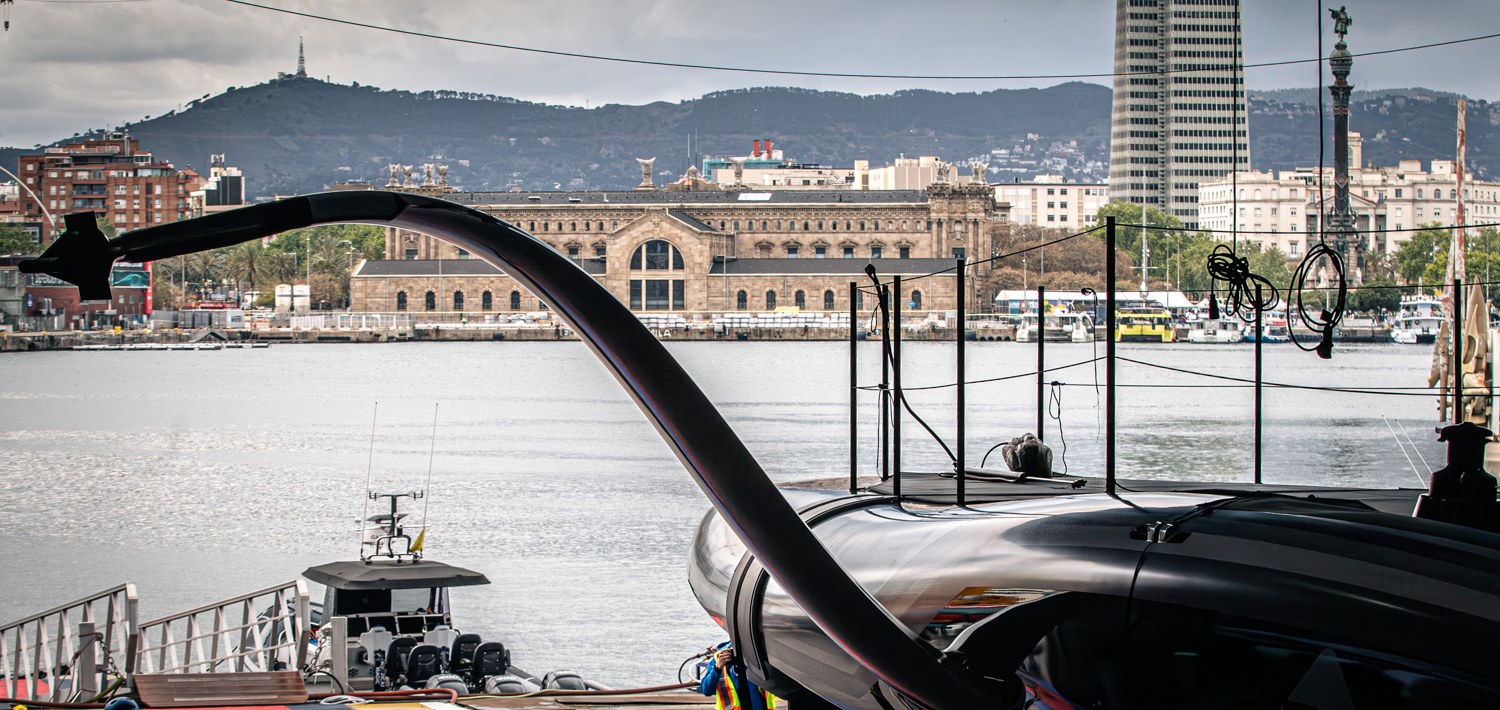 New York Yacht Club American Magic AC75 boat leaves the shipyard with Barcelona visible from the teams headquarters