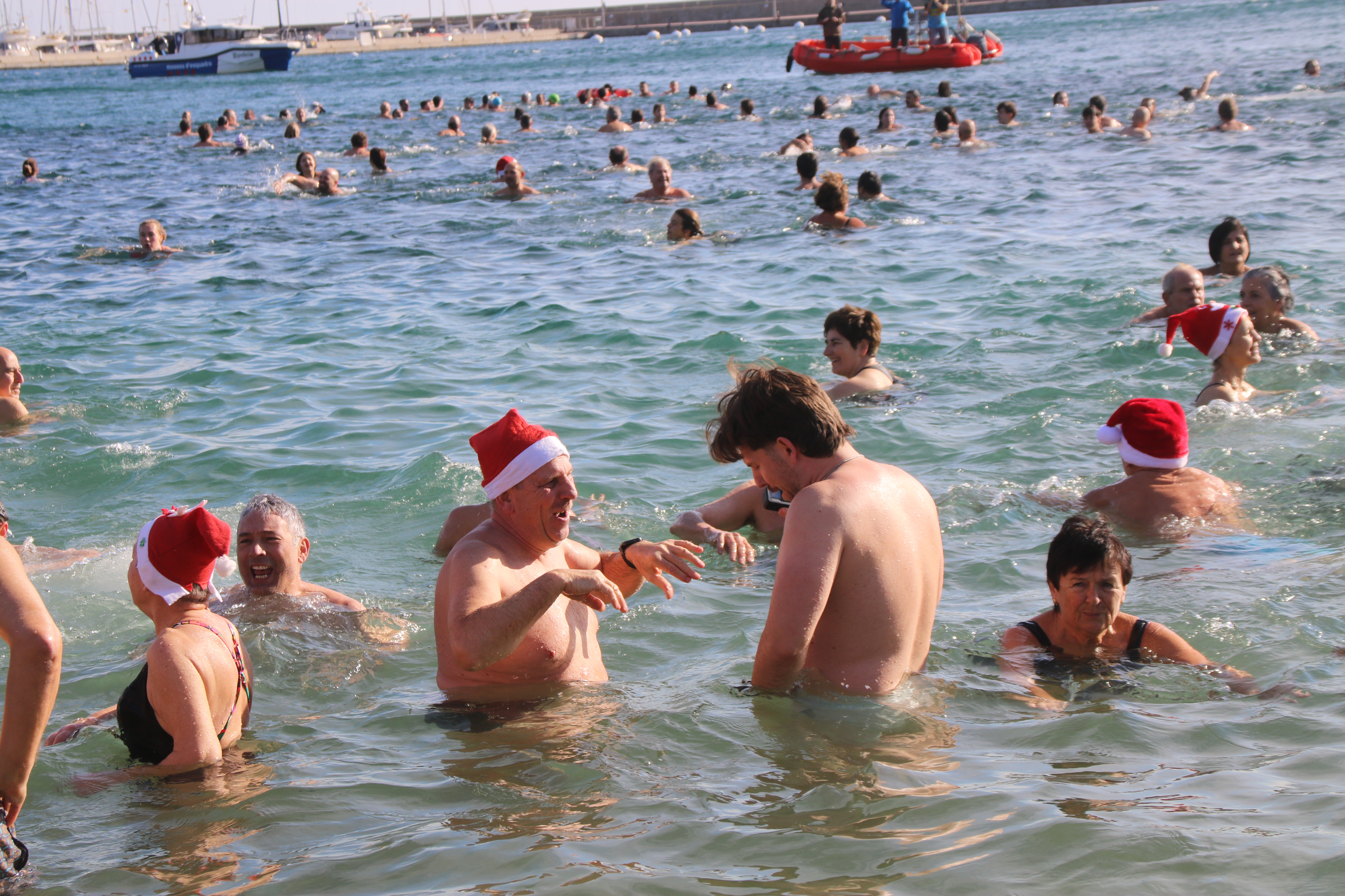 Dos homes, xerrant dins l'aigua, en el primer bany de l'any de Sant Feliu de Guíxols