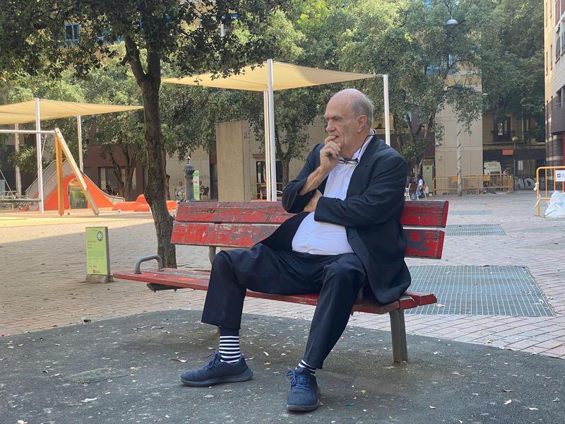 Irish author Colm Tóibín sitting on a red bench