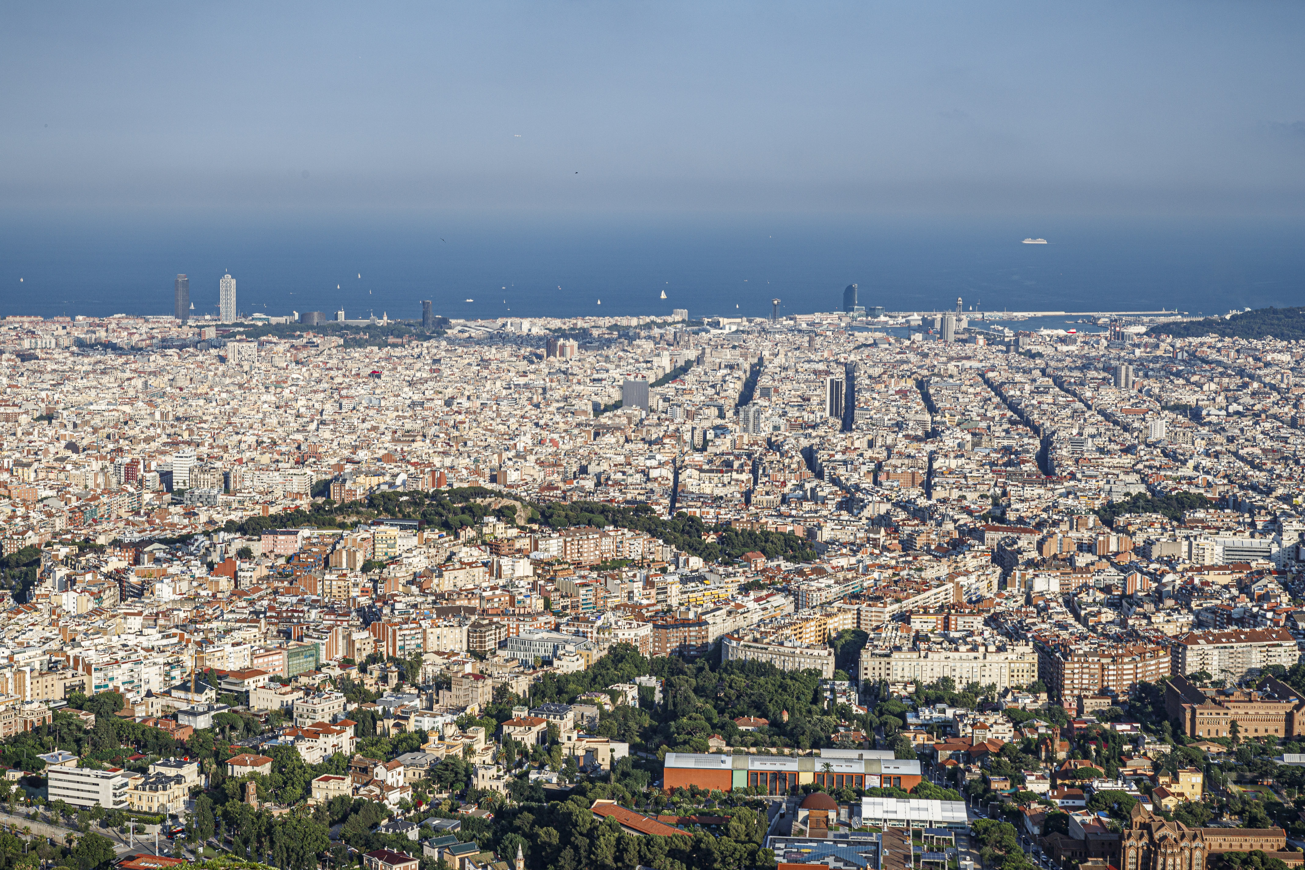 A panoramic view of Barcelona from Collserola mountain with views to the Eixample neighborhood, the Mediterranean Sea, and the Hotel Arts and Mapfre towers