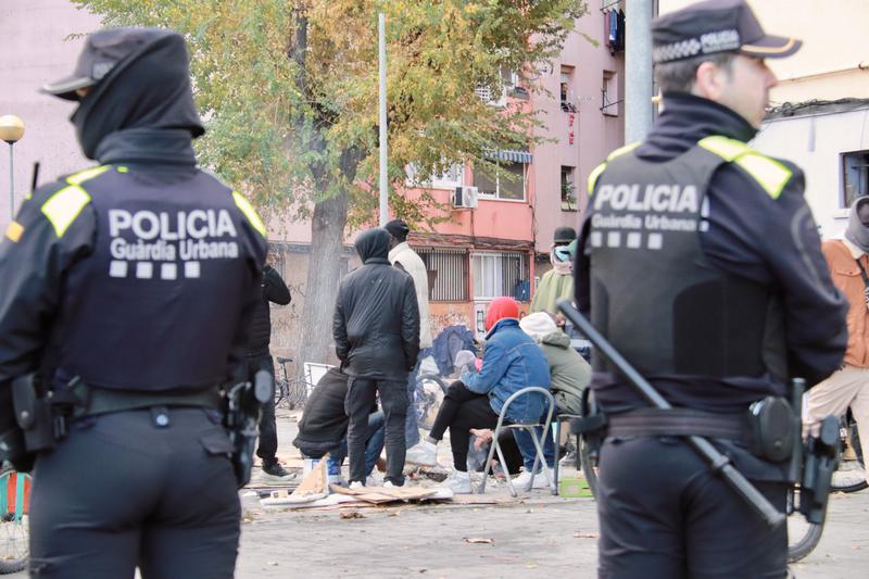 Badalona police officers in front of several migrants sleeping outside the B9 old High School on December 19, 2025