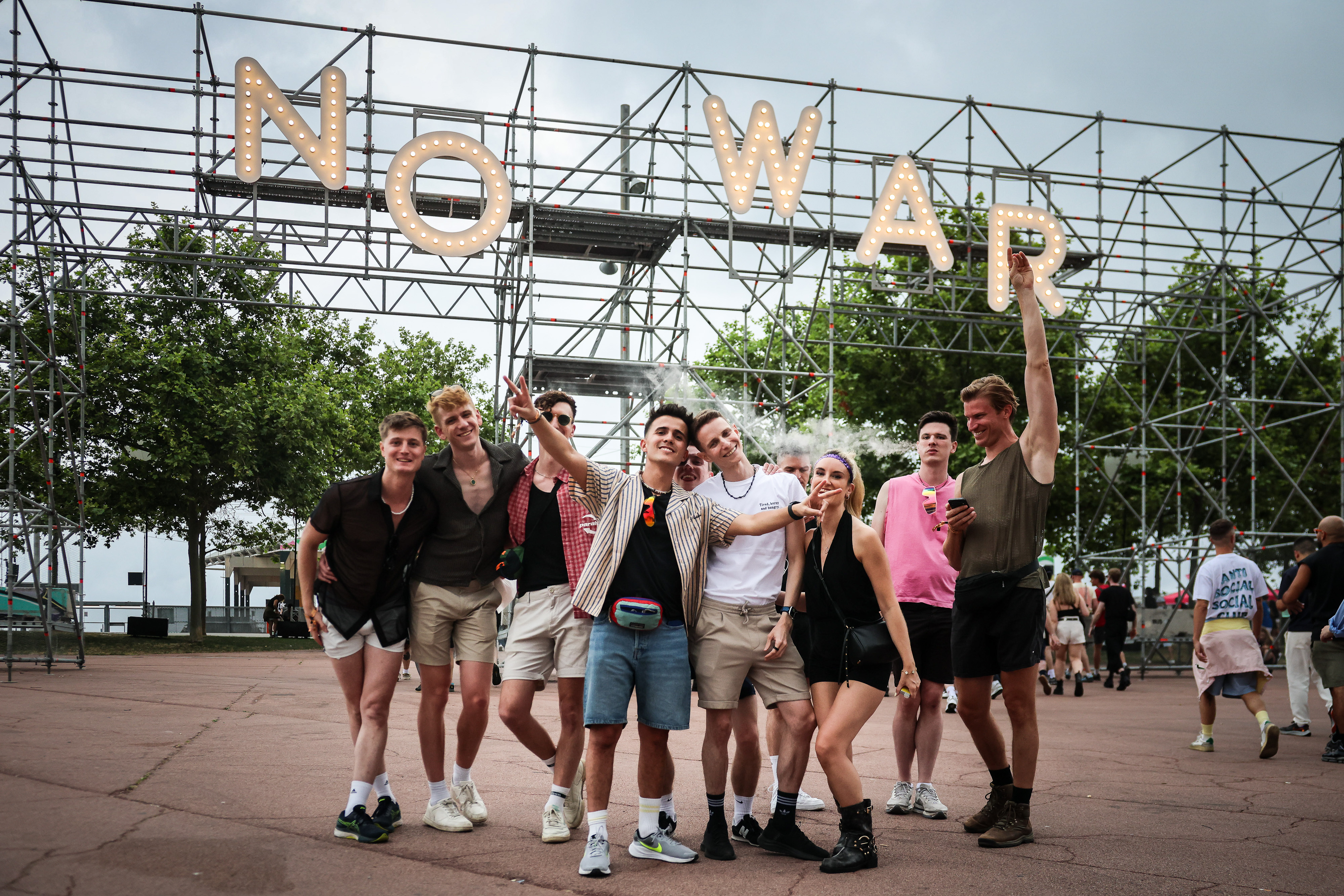 A group poses for a Photograph in front of a 'No War' sign at Primavera Sound