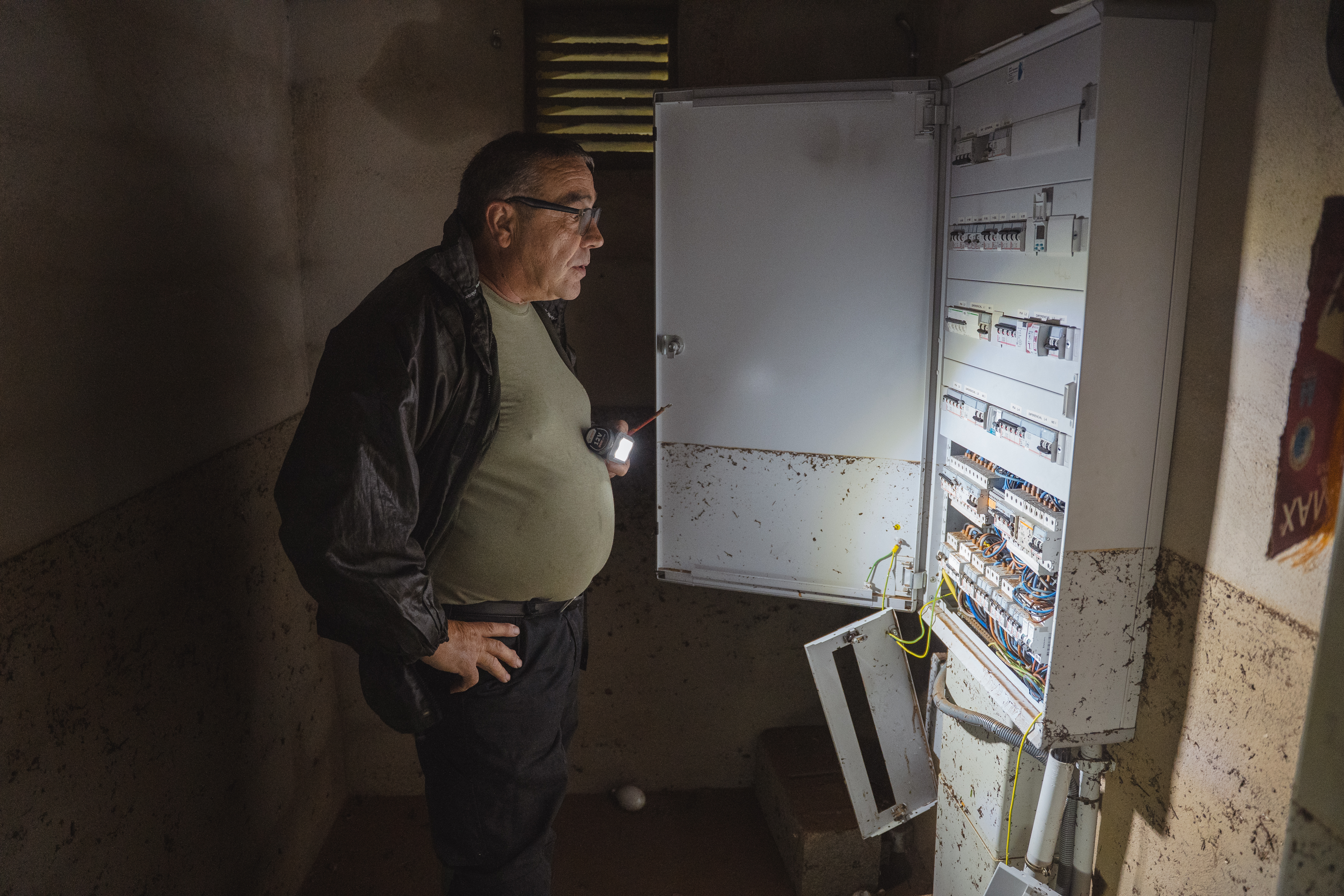 One of the residents in Godall, a municipality in the south of Catalonia, checks the electricity after light went out due to torrential rain on October 13, 2025