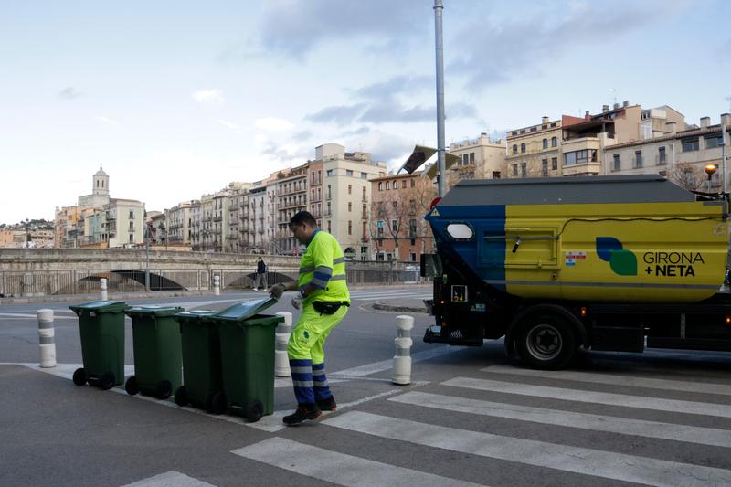 A waste collection worker in Girona picks up glass containers from a restaurant