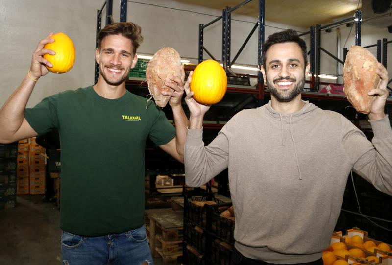 Oriol Aldomà and Marc Ibos, CEOs and founders of Talkual, display melons and sweet potatoes their company has saved from being thrown out
