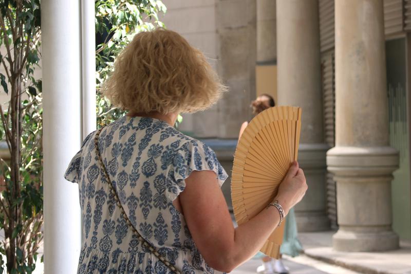 A woman cools herself off with a fan