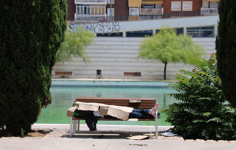 A homeless person protects themselves from the summer heat