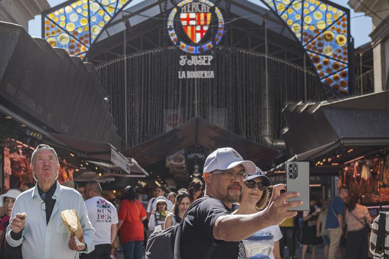 Tourists taking a selfie in front of La Boqueria market in Barcelona