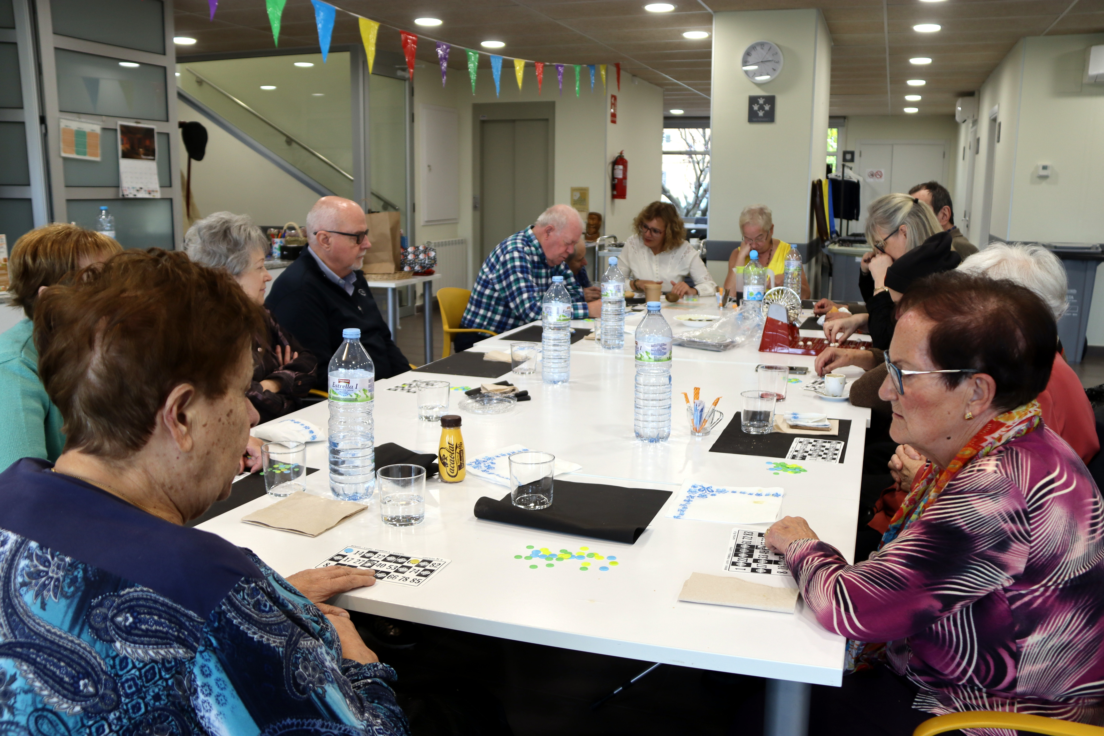 Participants in the 'Entaula’t' communal lunch play bingo after their meal