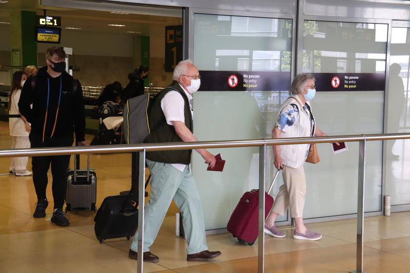 Passengers walk through Girona airport wearing face masks, June 2021