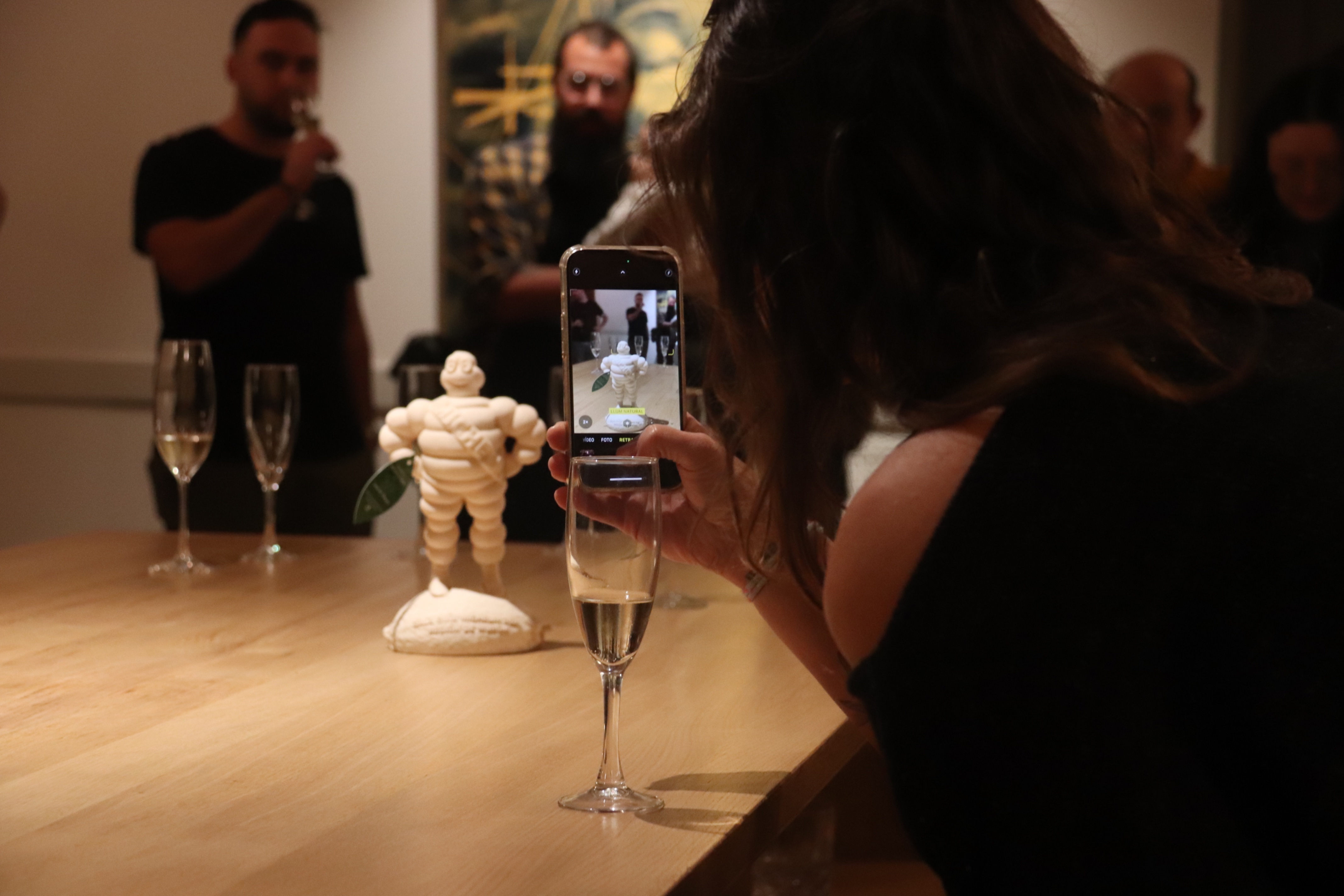 A woman takes a picture of a Michelin statuette at Divinum