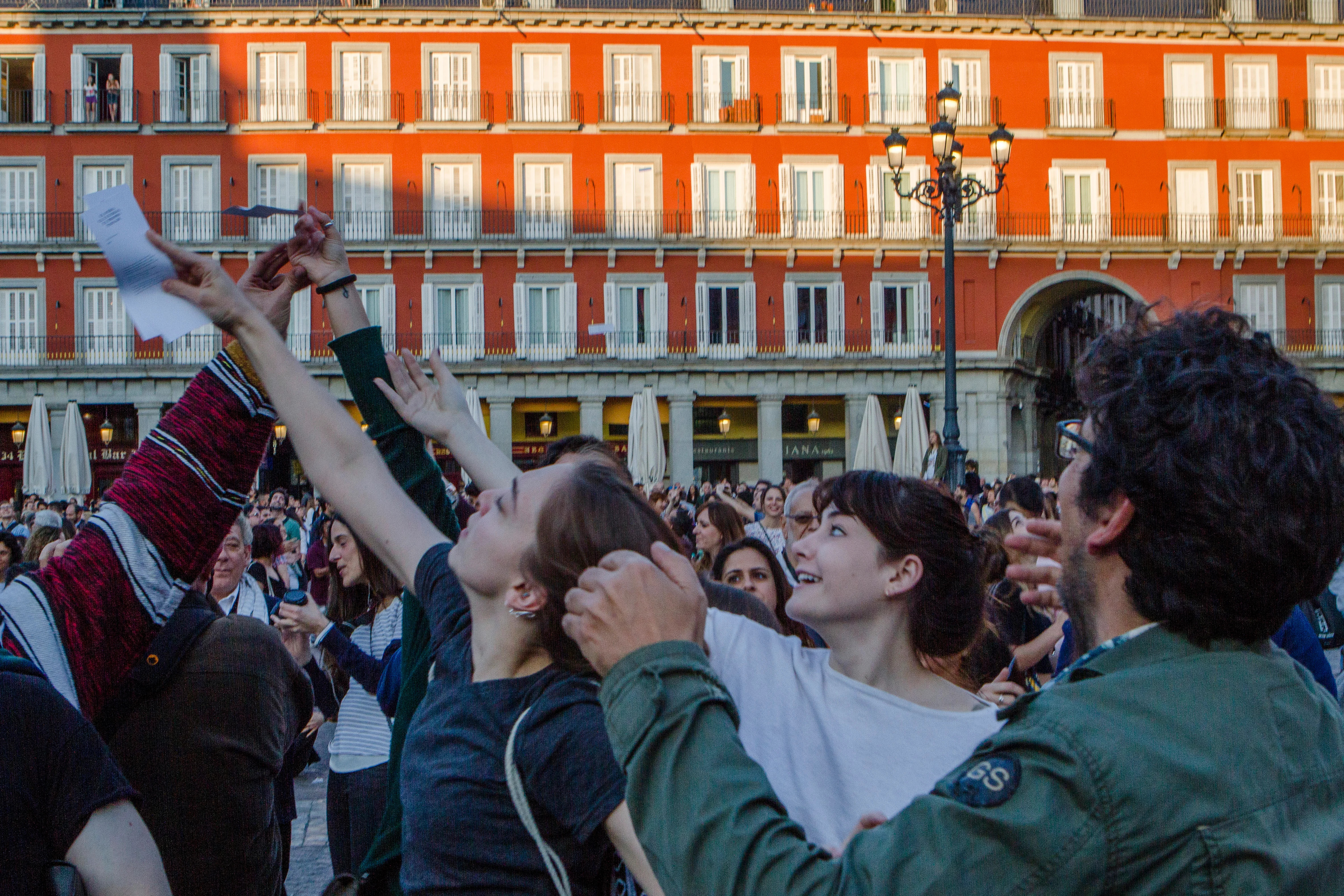 Spectators reaching for falling poems at the bombardment of Poems on Madrid, at the Plaza Mayor on May 31, 2018