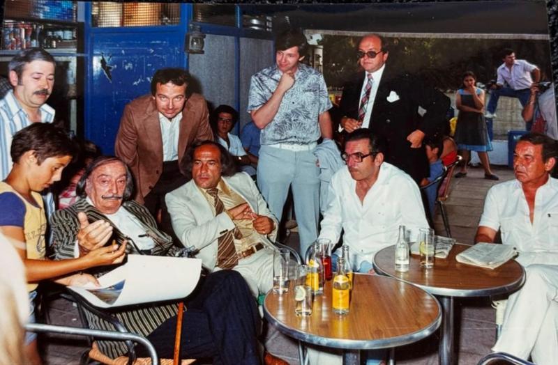 Catalan painter Salvador Dalí signs autographs while enjoying a drink at the Boia bar during the late 1970s