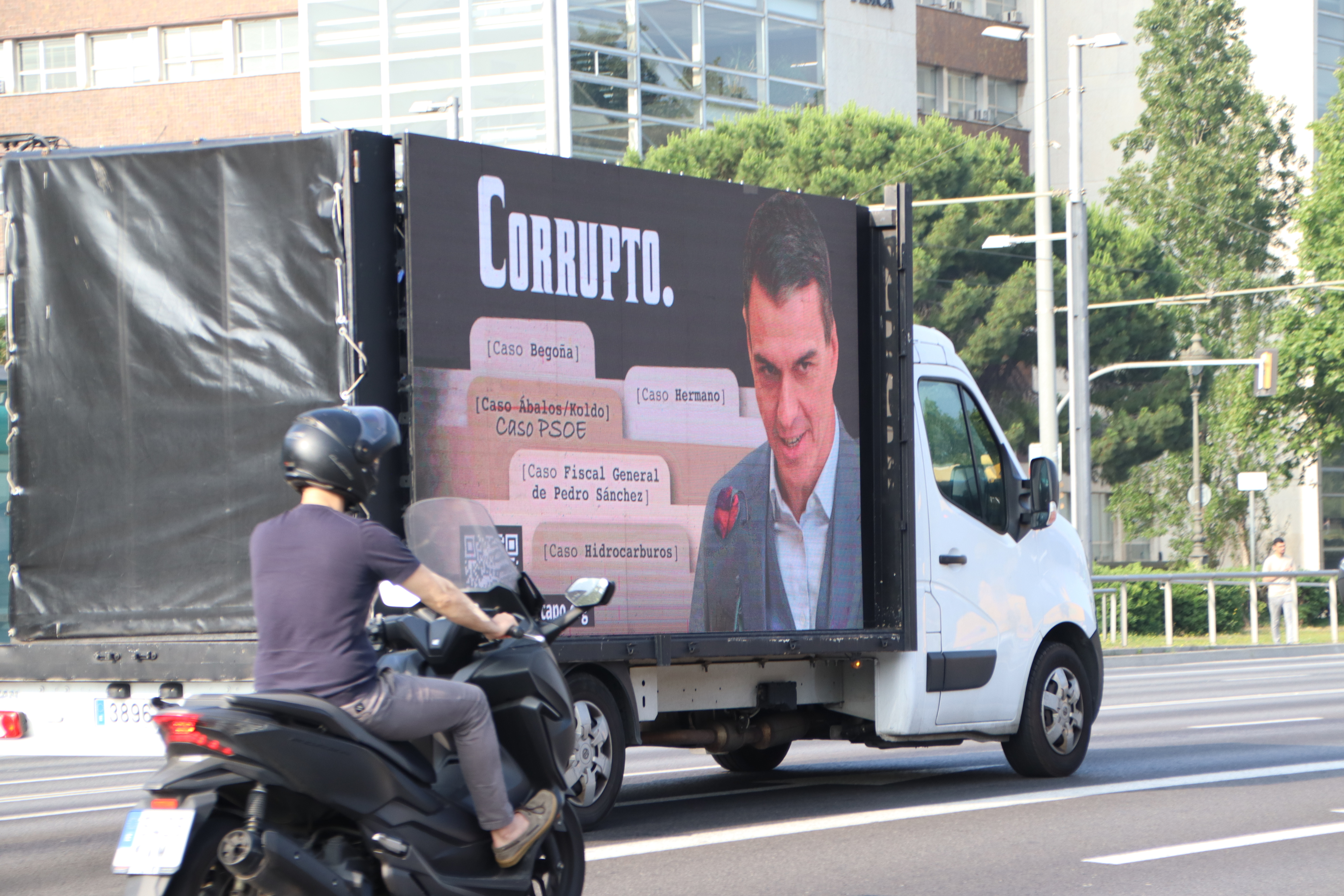 A coach bearing the image of Pedro Sánchez and the word "corrupt" in large letter driven along Avinguda Diagonal