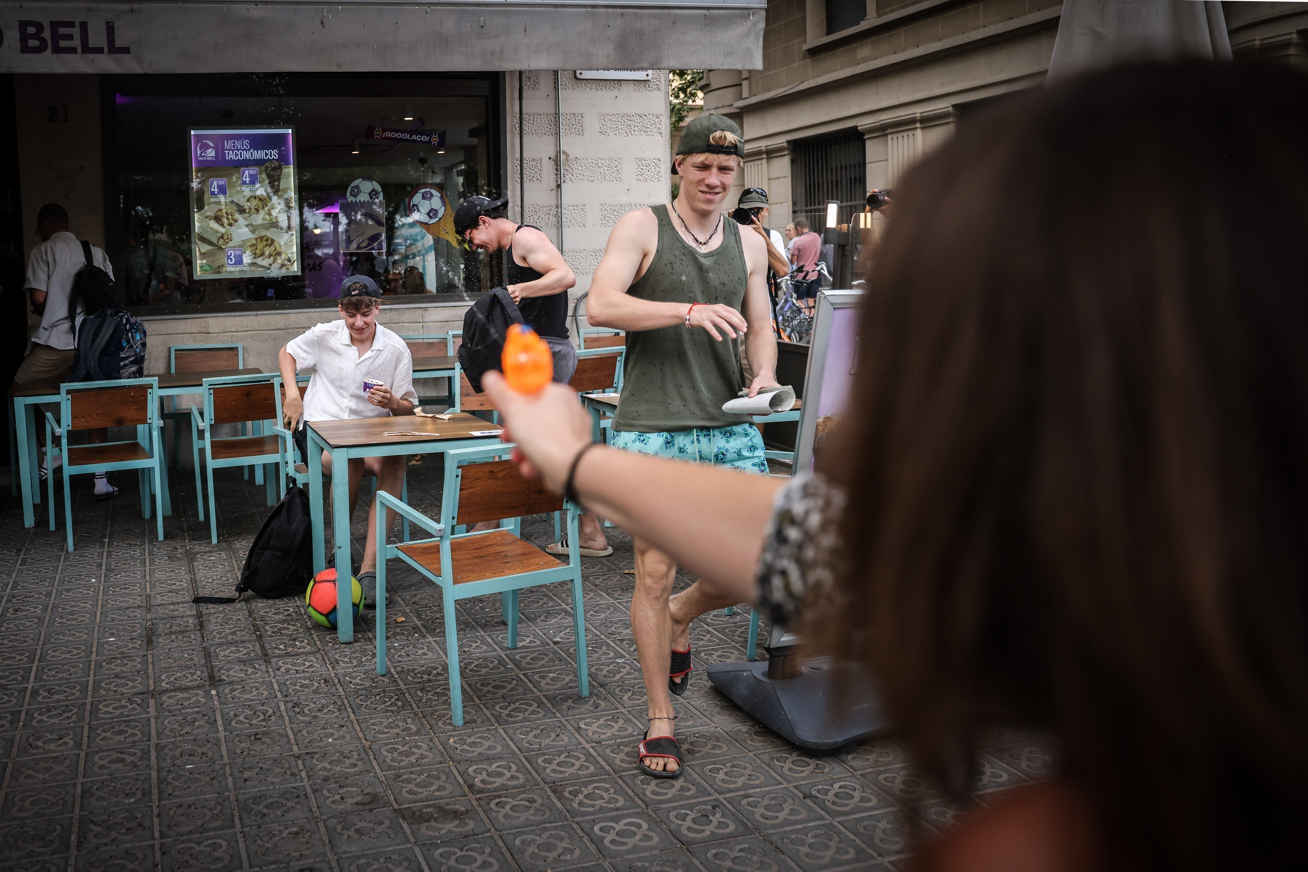 A woman squirts water at a group of tourists with an orange pistol in Barcelona on July 6, 2024 during a protest against mass tourism