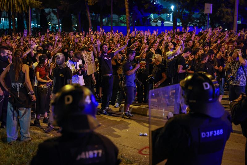 Two police officers facing demonstrators during a protest over the housing crisis at the Barcelona Congress Hall