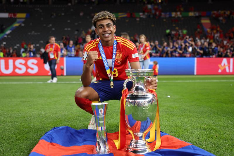 Lamine Yamal poses with the Best Young Player trophy and the UEFA Euro 2024 Henri Delaunay Trophy after victory over England in the UEFA EURO 2024 final match between Spain and England at Olympiastadion on July 14, 2024