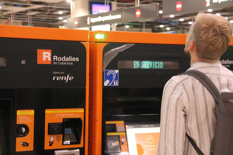 A passenger at a Rodalies ticket machine at Barcelona-Sants station