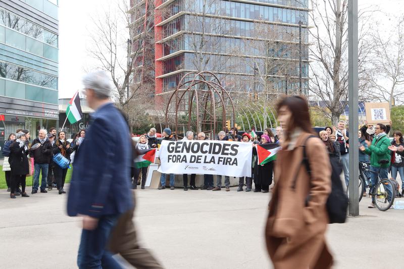 MWC attendees walk in front of a protest against Israeli companies at the tech fair held in Barcelona on March 3, 2025