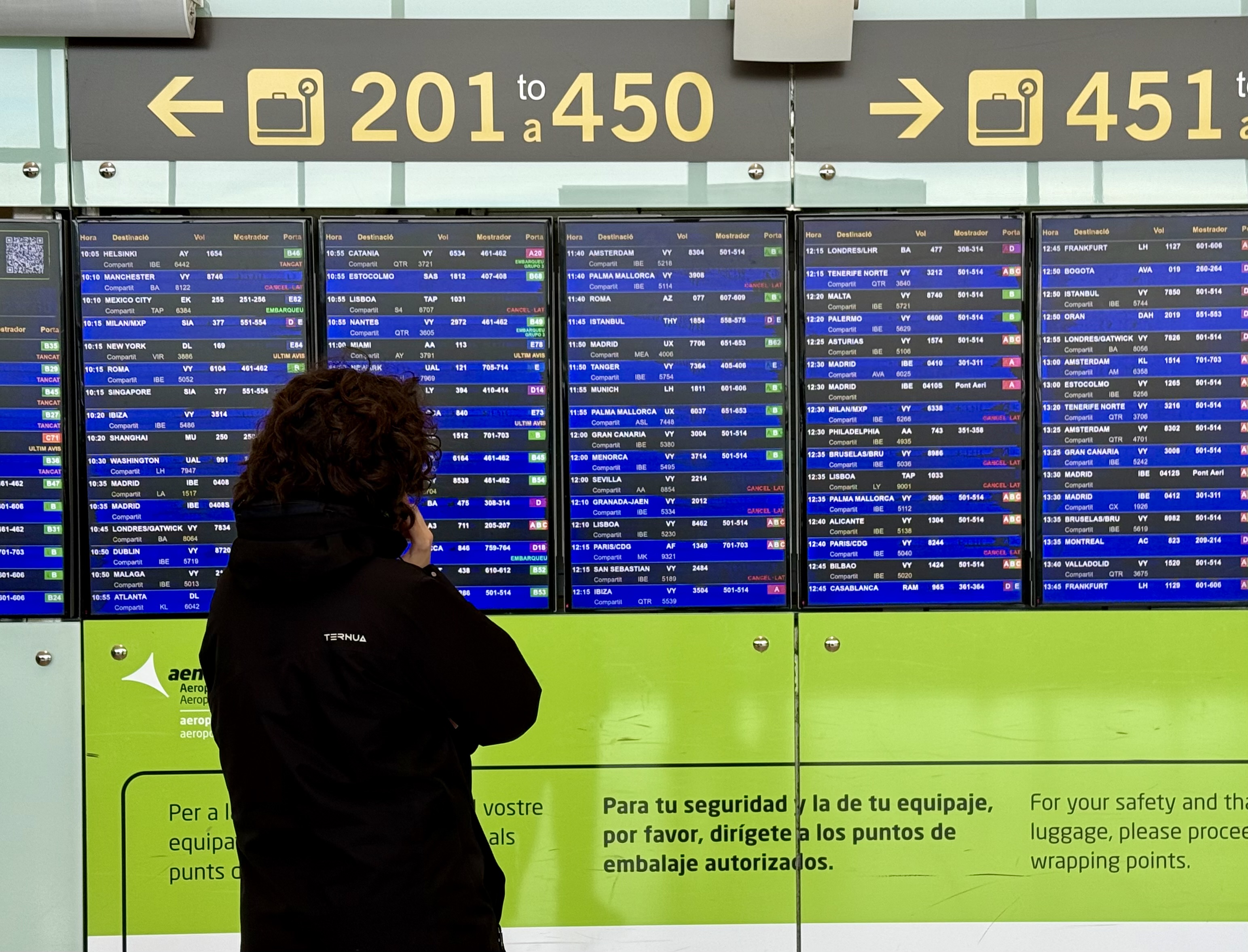 Una usuària mirant un panell informatiu a la Terminal 1 de l’aeroport del Prat