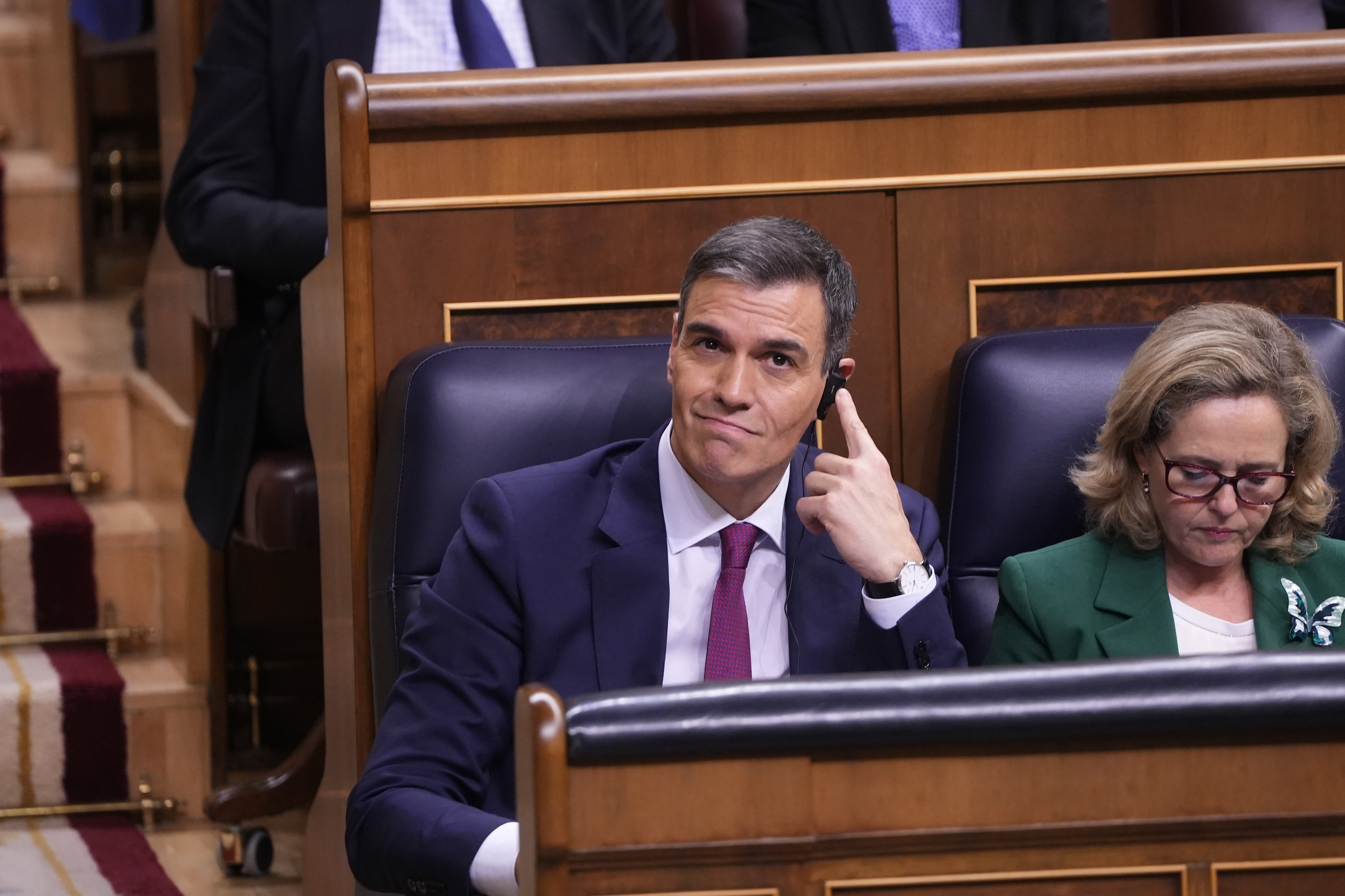 Socialist PM candidate Pedro Sánchez uses a live translator headphone to listen to Junts spokesperson Míriam Nogueras on November 15, 2023