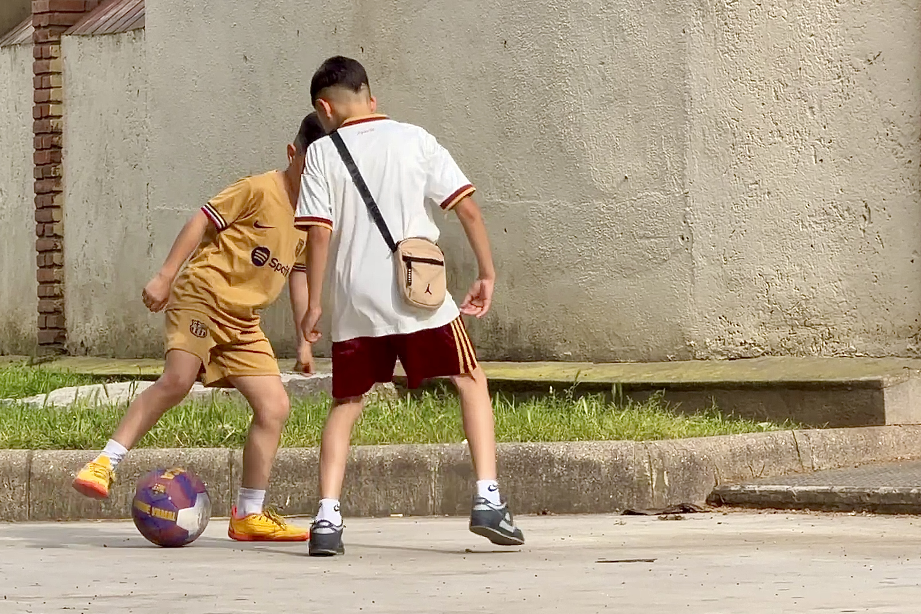 Two boys play football in a square in the Sant Roc neighbourhood of Badalona