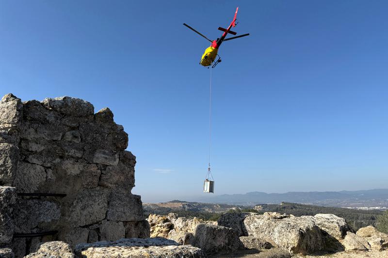 A helicopter lifts materials to the summit of Olèrdola Castle