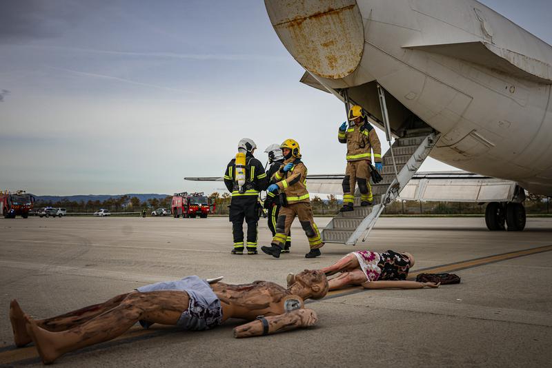 Firefighters beside an airplane and some figures representing injured people during a drill in Barcelona airport on November 20, 2024