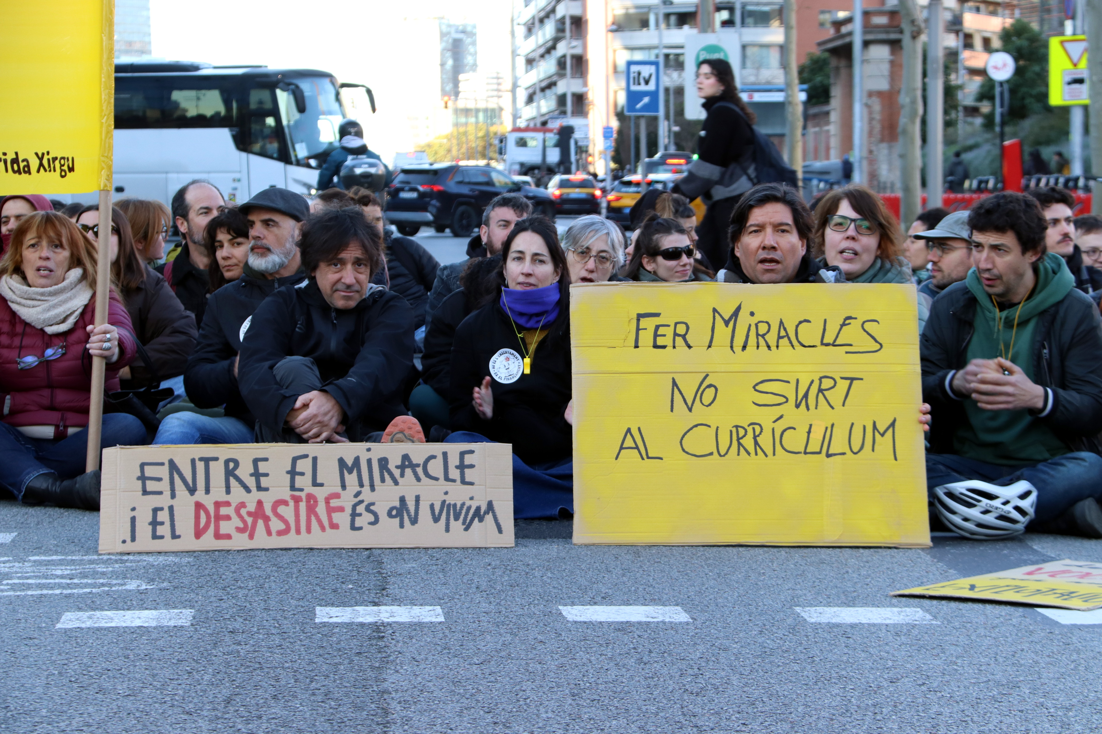 Striking teachers block Barcelona's Gran Via holding signs reading "Between the miracle and the disaster is where we live" and "Performing miracles is not in the curriculum"