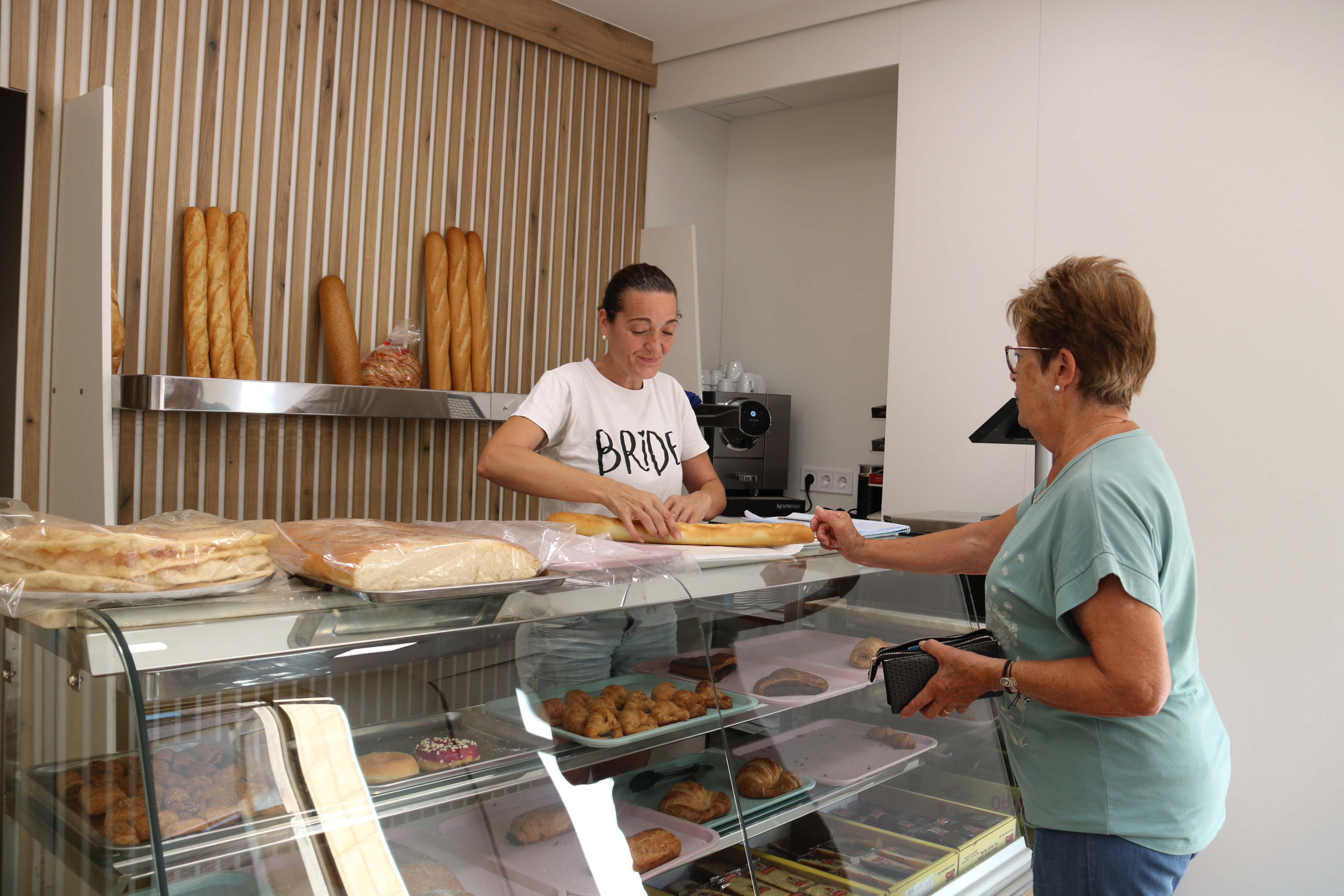 The owner of the new Cal Ventura bakery in Cervià de les Garrigues selling a loaf of bread to a customer
