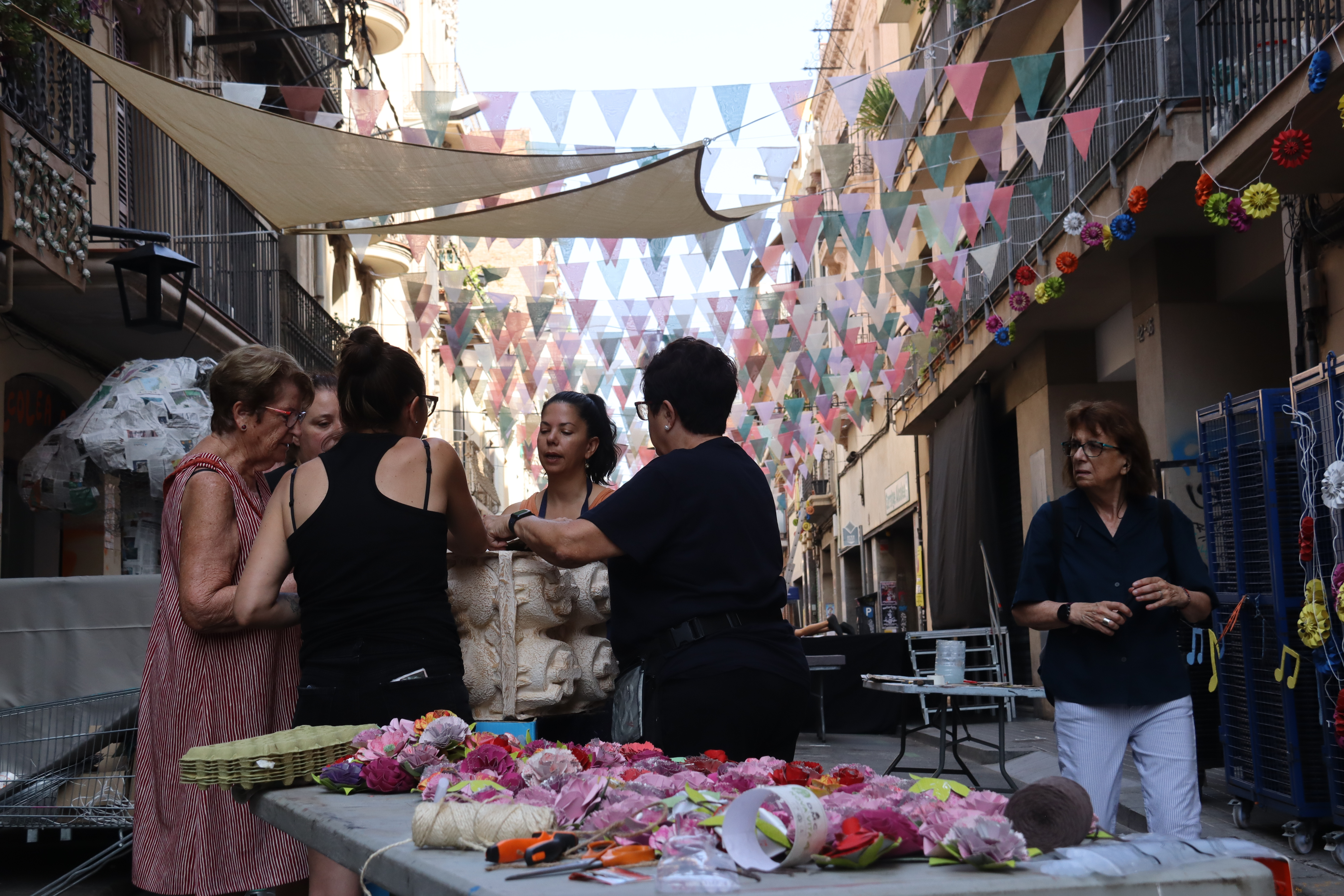 Un grup de dones enllesteixen la decoració del carrer d'Alcolea de Baix