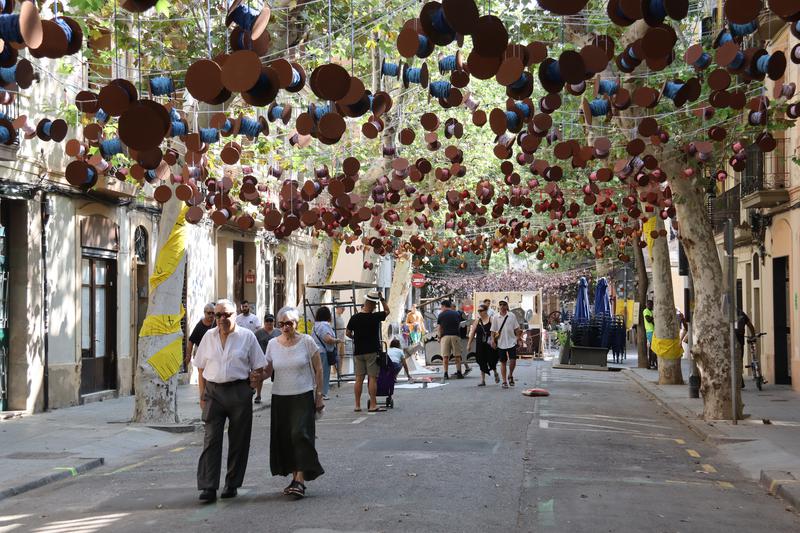 People walking through Carrer Valladolid decorated as part of the Festes de Sants