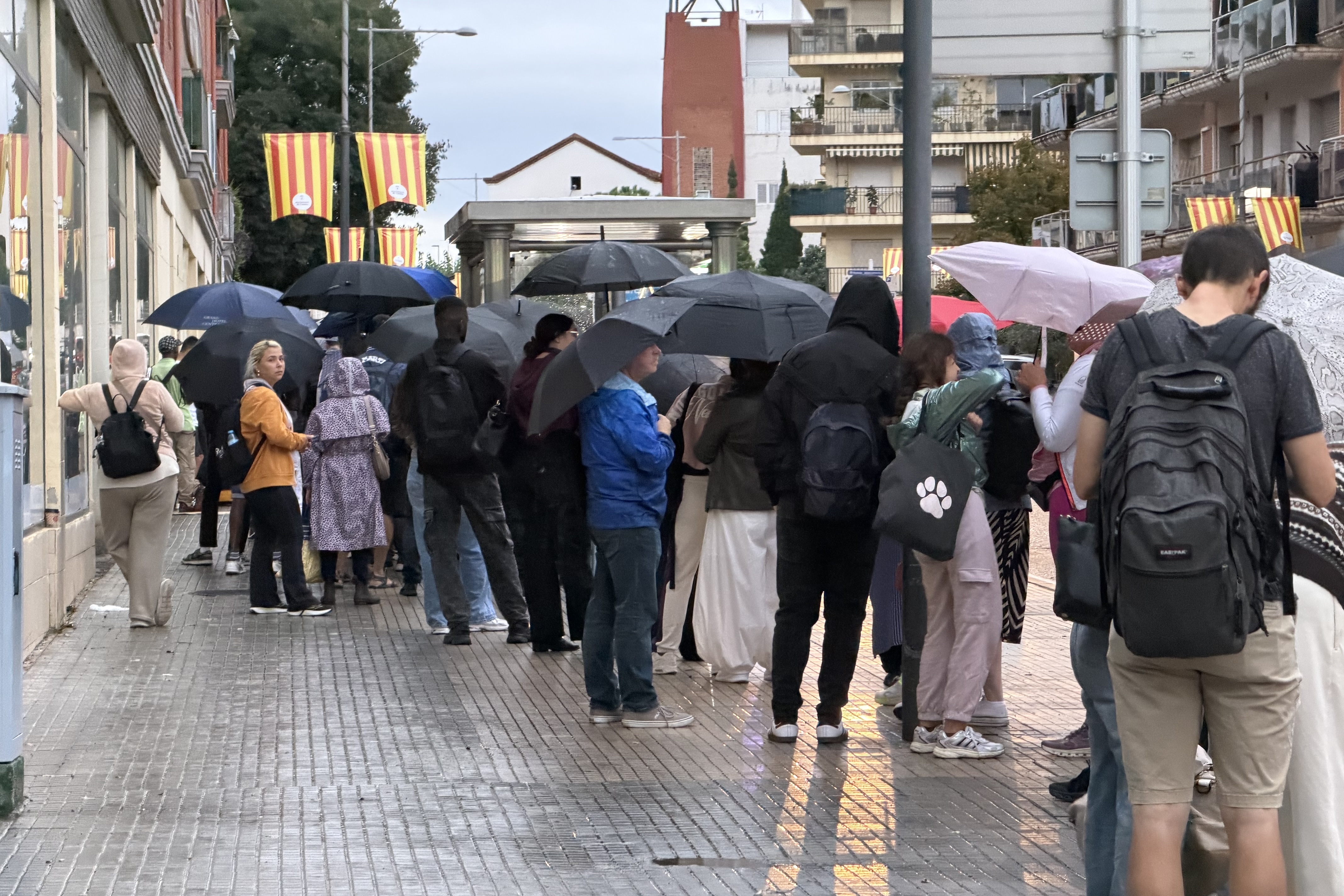 Commuters queuing in the rain in Calella to catch one of the buses provided by Renfe.