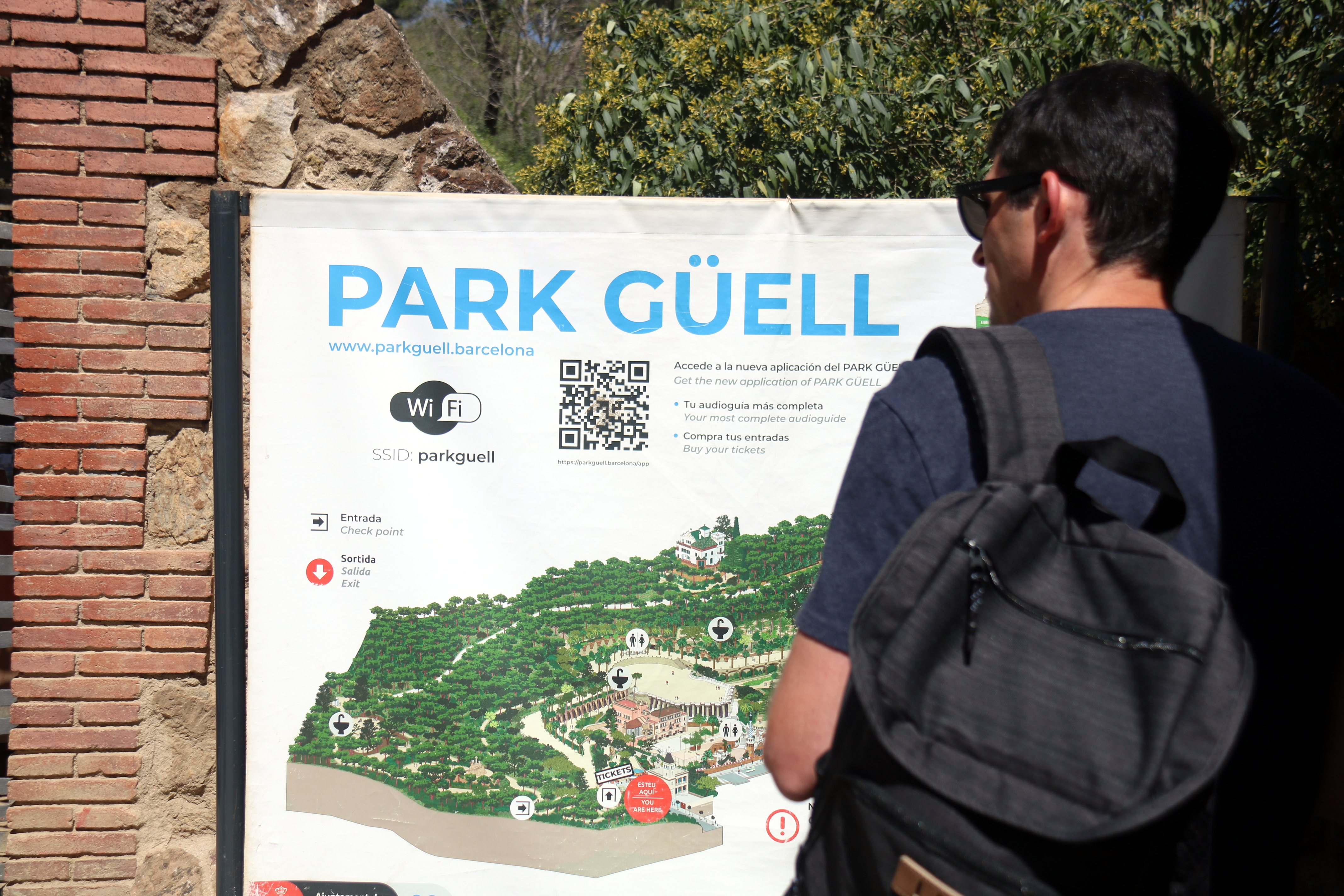 Un turista davant d'un cartell amb un plànol del Park Güell.