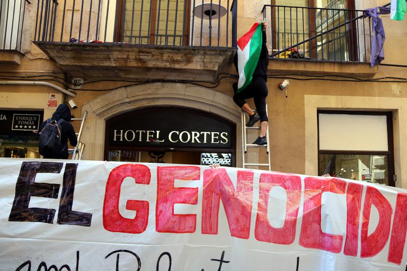 Pro-Palestine protesters hang Palestinian flags on the façade of Barcelona's Cortés Hotel, owned by an Israeli tycoon, on October 21, 2023