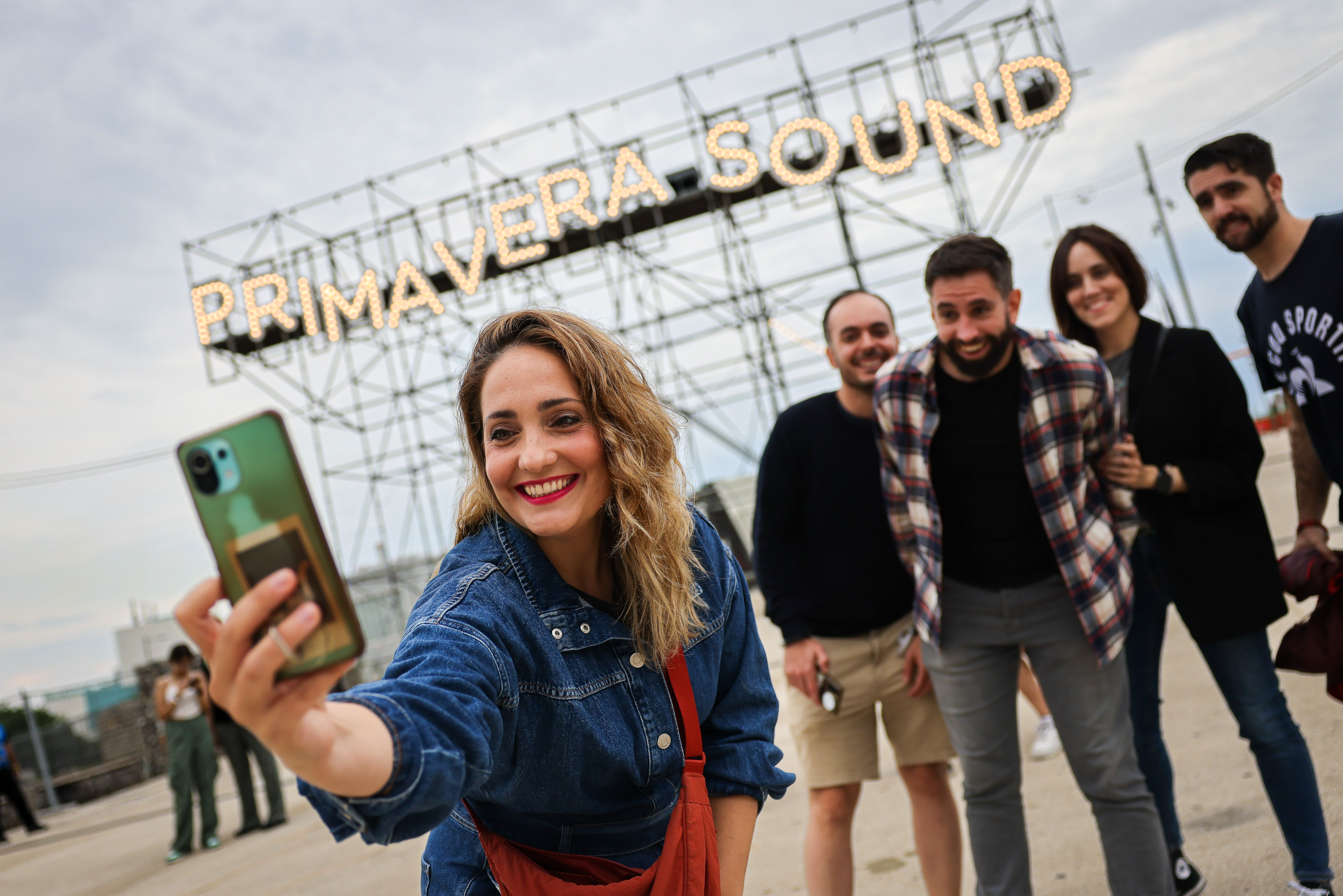 A group of friends taking a selfie in front of the Primavera Sound poster in Barcelona on May 31, 2023