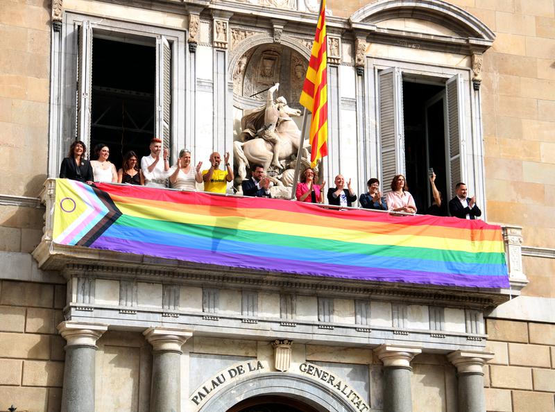 A Pride flag is hung over the entrance to the Palau de la Generalitat, with President Pere Aragonès, ministers and activists.
