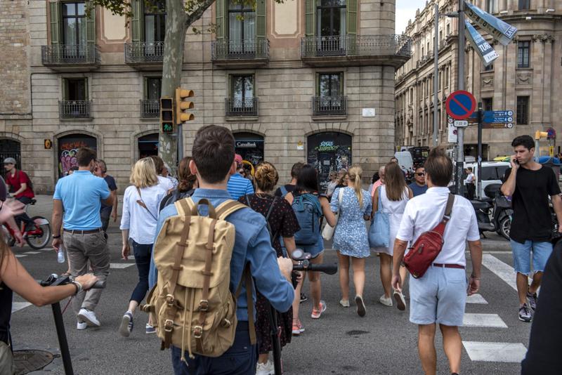 Dozens of people crossing a zebra crossing in one of Barcelona's mass tourism districts